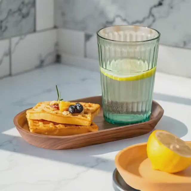 Glass of lemon water and waffles placed on Mokura oval tray in bright kitchen corner